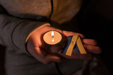 The girl holds a burning candle and a yellow-blue ribbon in her hands (the national symbol of...