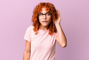 redhair pretty woman looking serious and curious, listening, trying to hear a secret conversation...