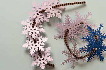 collection of mostly pink and blue paper snowflakes strung on pipe cleaners