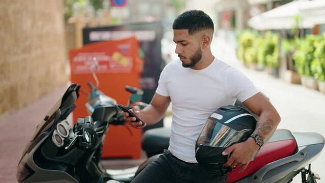 Young latin man make selfie by smartphone standing by motorbike at street