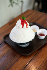 Korean shaved ice dessert with sweet toppings, Strawberry Bingsu on wood table
