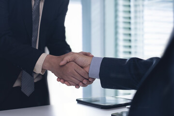 Business man in black suit shaking hands to agree a business partnership agreement. Business...