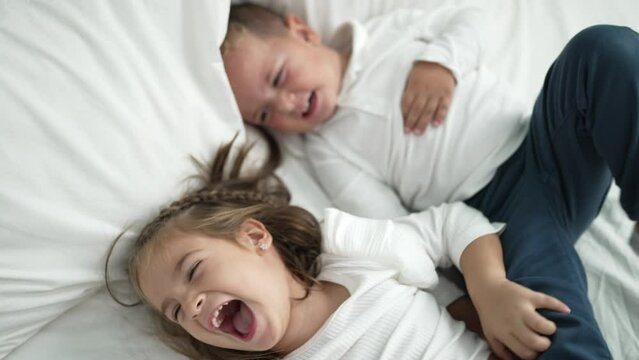 Adorable girl and boy laying on bed playing at bedroom
