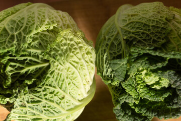 Fototapeta premium Close up - two savoy cabbage on a wooden blurred background - top view