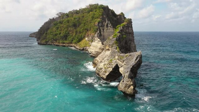 Aerial orbit view of rock formation with natural arch, Nusa Penida, Bali