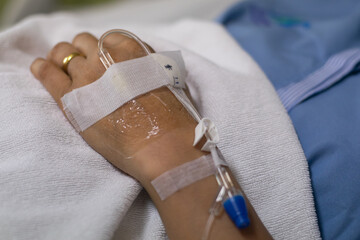 woman patient  speep in bed  with IV  drip on hand in room at hospital alone.