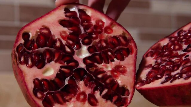 Halves of Pomegranate Displayed by Woman's Hands