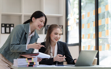 Female business worker with colleagues in Thailand working together at office desk, Female office worker business suit working with document file and paper work.