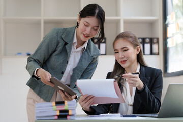 Fototapeta na wymiar Female business worker with colleagues in Thailand working together at office desk, Female office worker business suit working with document file and paper work.