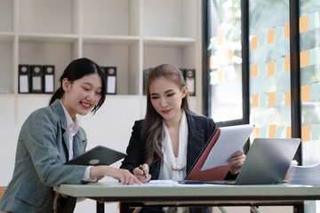 Female business worker with colleagues in Thailand working together at office desk, Female office worker business suit working with document file and paper work.