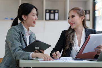 Female business worker with colleagues in Thailand working together at office desk, Female office worker business suit working with document file and paper work.