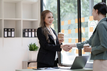 Female business worker with colleagues in Thailand working together at office desk, getting shaking hands, successful and agreement concept