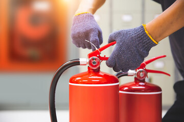 Fire extinguisher has hand engineer checking safety pin to prepare fire equipment for protection...