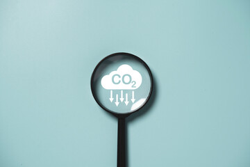 CO2 reducing icon inside magnifier glass for focusing decrease CO2 or carbon dioxide emission...