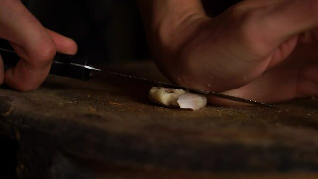 Horizontal video of a garlic crushed by a knife on a board. Food.