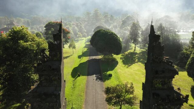 Aerial view flying through temple gate with balinese woman standing in the middle, Bali, Indonesia