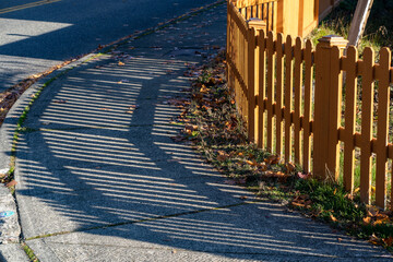 Fence and shadow on sidewalk rounding a corner