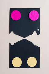two black paper shapes with pink and yellow circles