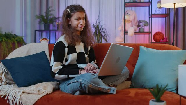 Portrait of caucasian preteen girl use laptop typing browsing working, loses becoming surprised sudden lottery results, bad news, fortune loss, game fail. Young child kid at home in play room on couch