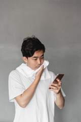 Asian man is wiping sweat while using mobile phone.
