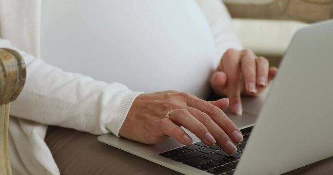 Pregnant freelance employee woman working from home, typing on laptop at big 9 months belly indoors, using online app, chatting, shopping on Internet, consulting doctor. Cropped shot