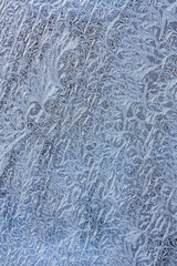 light blue frozen glass background. ice crystals on frosted winter window.