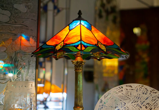 Multi color glass lamp . Interesting interior. Tiffany lamp on wooden  table. Stained glass lamp, with a lampshade of colourful glass mosaic in  green, yellow and red. Stock-Foto | Adobe Stock