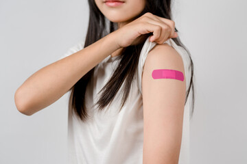 Happy young woman after getting a vaccine. showing shoulder arm with bandage after receiving vaccination, herd immunity, side effect, booster dose, vaccine passport and Coronavirus pandemic