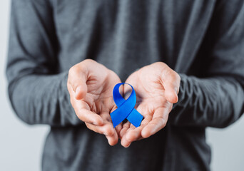 men hands showing Blue ribbon for supporting people living and illness, Colon cancer, Colorectal cancer, Child Abuse awareness, world diabetes day, International Men's Day