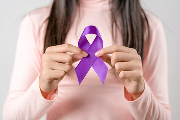 woman hands holding purple ribbon, Alzheimer disease, Pancreatic cancer, Epilepsy awareness, world cancer day on a purple colored background, World Cancer Day concept