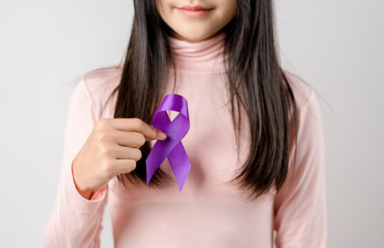 woman hands holding purple ribbon, Alzheimer disease, Pancreatic cancer, Epilepsy awareness, world cancer day on a purple colored background, World Cancer Day concept