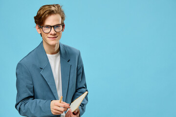 a funny guy in a strict suit for office work is wearing glasses and holding an empty notepad in his hands
