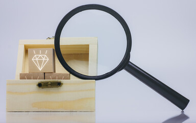 Wooden treasure box and diamond icon inside, magnifying glass, isolated on white background.