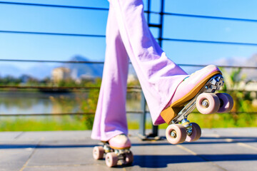close up photo of feet of woman in flared pink pants skating on rollers in park