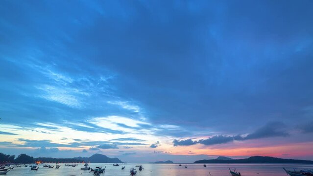 time lapse beautiful sunrise above fishing boats on Rawai beach, Phuket,Thailand..light through the cloud to sky above fishing boats..video 4K. Scene of Colorful red light in the sky background..