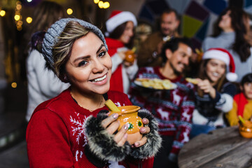 Hispanic young woman portrait holding a cup of fruit punch at traditional posada party for...
