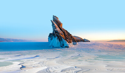 Beautiful winter landscape of frozen Lake Baikal at sunrise - A granite rock with steep slopes rises above a frozen lake - Baikal lake, Siberia