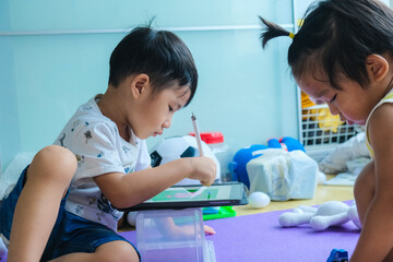 Obraz na płótnie Canvas Kindergarten child boy and girl drawing image with tablet