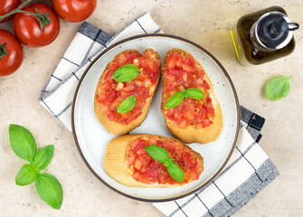 Crispy bruschetta with tomatoes, herbs and olive oil on a white plate, top view. Italian appetizers.