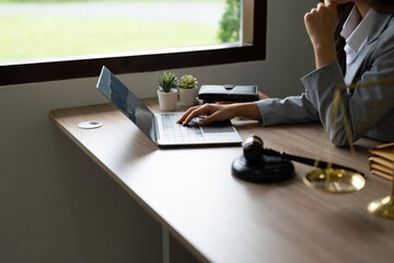 Fototapeta premium justice and law concept.Male judge in a courtroom on wooden table and Counselor or Closeup lawyer working with lsptop in office. Legal law, advice and justice concept.