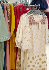 Female casual clothes in boutique, clothes with a selection of ladies fashion, Colorful women's dresses on hangers in a retail shop in India.