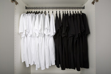 black and white t-shirts hang on a clothes rail in a white wardrobe. all t-shirts are only two...