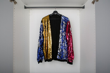 single multicoloured sequin party cardigan on clothes rail in empty white wardrobe or closet