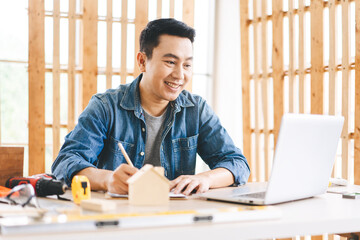 Middle age adult asian man carpenter using laptop for online working with customer wotk at home