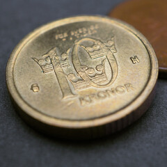 Swedish coins lie on a dark surface. 10 ten krona coin close up. National currency of Sweden. Money crown square illustration for news about economy. Banking and credit. Wages and taxes. Macro