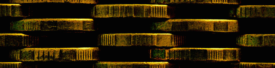 Naklejka premium Stacks of coins close-up. Money textured header. Dark brown abstract banner made of many coin edges. Image with high contrast and saturation. Economy finance and banking. Macro