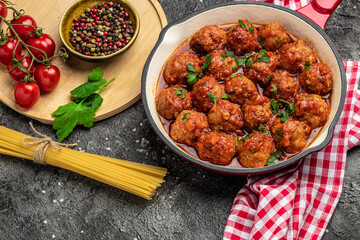 Meatballs with tomato sauce in frying pan on black background, top view