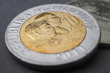 Philippine money lie on a dark surface. Coin of 10 ten pesos close-up. Peso of Philippines. News about economy or currency. Loan and credit. Money and taxes. Philippine peso. Macro