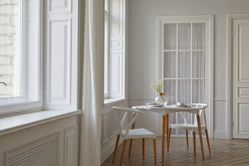 Interior of contemporary light room with white walls and big windows round table with two chairs and glass vase on it