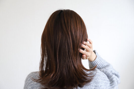 髪の毛を触る女性の後ろ姿